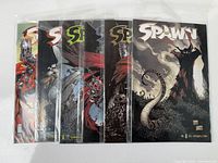 Six Spawn comic books in protective sleeves fanned out showing covers and edges.