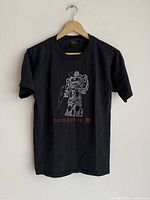 Front view of black vintage Transformers T-shirt with white line art Soundwave robot and red text.