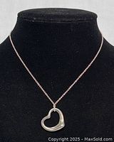 Front view of necklace on black bust, showing heart pendant suspended from chain