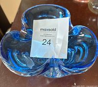 Top view of blue art glass bowl with a label on it, showing its shape and size.