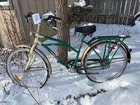 Side view showing green and cream frame, front and rear tires, rear rack, and handlebar with gripshifter.