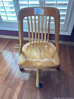 Front view of wooden swivel chair showing contoured seat and vertical slat backrest.