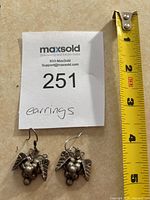 Pair of silver grape cluster earrings next to a measuring tape showing about 1.5 inches length.