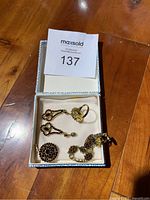 Photo of the jewelry set in a box showing earrings, ring, bracelet, and pendant charm with red gems and gold tone.