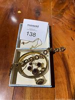 Photo showing full set of gold tone costume jewellery including necklace, bracelet, ring, earrings, and cuff bracelet in a box with auction tag.