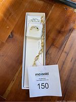 Overall view of gold tone ring and gold plated bracelet in a white box