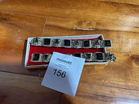 Two Mexico sterling silver bracelets featuring rectangular black stones and silver masks arranged alternately, placed inside a box with a red lining.