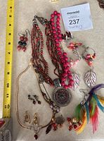 All jewelry items including two necklaces and multiple pairs of earrings displayed with yellow measuring tape for scale.