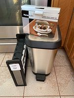 Three kitchen items grouped: plastic spice rack with 8 jars, stainless steel waste basket, and boxed Home Styles 3-piece gravy boat set
