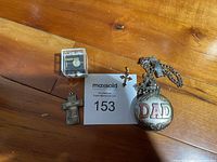 Photo showing all items together on wooden surface: Gruen pocket watch with DAD inscription, small cross with red gems necklace charm, 'My Guiding Cross' cross charm, and sterling silver praying hands pin.