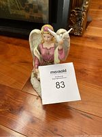 Front view of Royal Doulton Angel of Peace porcelain figurine holding a scroll and a white dove, seated on a cloud base.