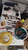Wide view of table with various hand tools including wrenches, hammer, screwdrivers, pliers, tape measures, et cetera.