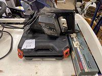Black & Decker belt sander model 7447-04 placed on top of its carrying case showing side view.