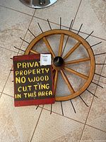 Wooden wagon wheel and metal sign together on tiled floor