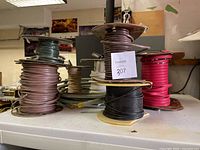Multiple spools of wires and cables in different colors and spool materials arranged on a counter