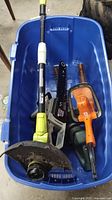 Mastercraft chainsaw, Ryobi weed wacker, two Black & Decker hedge trimmers placed inside a blue plastic storage bin on garage floor
