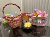 Wide view of all items in the lot showing three Easter-themed baskets and a small chick ornament on a black surface.