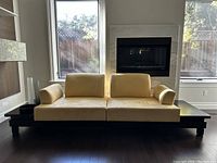 Full front view of pale yellow suede modular sofa on dark wood platform base.