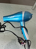 Blue BaBylissPRO Nano Titanium hair blow dryer with attached power cord and control switch placed on glass table.