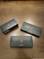 Three black boxes with Peloton branding arranged on a wooden surface showing items included in lot