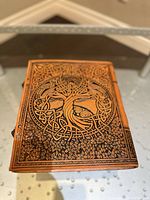 Front cover view showing embossed tree of life design on leather journal