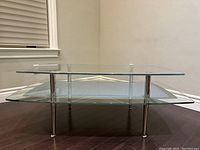 Front view of the two-tier glass coffee table showing clear glass top and textured bottom shelf with chrome legs