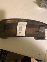 Side view of metal guillotine cutter showing the long curved blade and base with rust spots