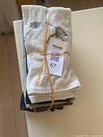 Stack of 9 hand towels folded and bound with rubber bands showing one towel with tree design.