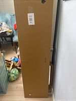 Tall rectangular box sealed, shipping label visible, held upright, packaging intact indicating new condition.