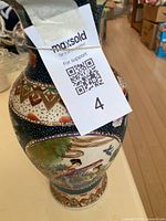 Full view of porcelain oriental vase with hand-painted scene of figures and birds, QR tag attached.