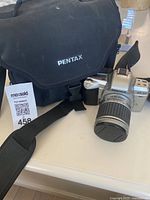 Pentax MZ-60 camera with attached zoom lens and original case, front view