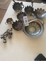 Top-down photo showing the assorted silver plated dishes, creamer jug, candle holders, and decorative basket with handle.