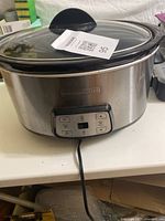 Front angle view showing the stainless steel body, digital control panel, and power cord of the Black & Decker slow cooker.