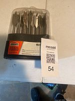 Plastic case holding spade drill bits, showing the label with brand Jobmate and total pieces 15 with 3 missing as stated by seller. Bits visible with rust on some.