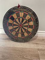 Full view of antique round dart board with National Darts Federation of Canada text and numbers around edge.