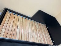 Front view of assembled black wooden bed frame with slats and headboard