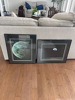 Two framed moon photographs leaning against couch, showing size comparison and style.