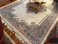 Overall view of ivory rug with floral border and fringe under coffee table in family room