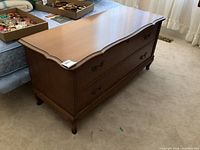 Full view of the cedar chest showing curved top, wood finish, and heavy solid construction.