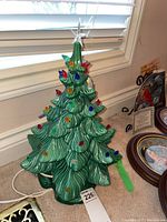 Full view of the ceramic Christmas tree showing green glossy textured branches and multi-colored lights attached