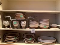 Shelves with stacked plates, bowls, goblets and platter visible