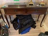 Front view of hall table showing two drawers, brass hardware and glass top