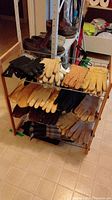 Full view of wooden frame shoe rack holding multiple pairs of leather gloves and mittens with shoes on top shelf.