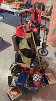 Photo of one golf bag with multiple clubs and a cart stand, surrounded by golf accessories and boxes including golf balls and covers.