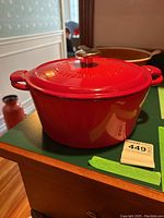 Red Henckels International Dutch oven on kitchen countertop with visible lid and metal knob, showing exterior and handles.