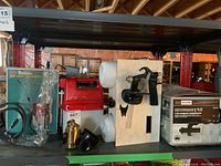 Photo showing Sunrise battery operated paint sprayer in original packaging along with Sears Craftsman accessory kit box and spray gun accessory on storage shelf.