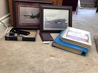 Overview of lot with two framed photos, manuals, passport wallet and pin box
