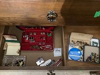 Drawer containing various cuff links and small pocket knives alongside several boxes with lapel pins and other memorabilia.
