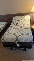 Full view of mattress on raised adjustable frame with remote on top