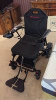Full front view of wheelchair with footrest down, joystick, seat and frame visible